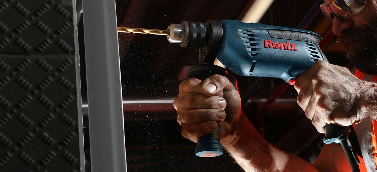 Close-up of brad nailer staple gun firing into wooden baseboard