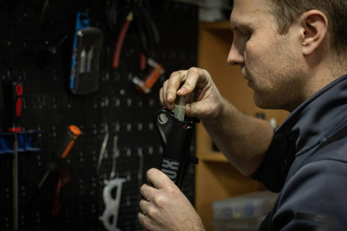 nail gun service repair technician testing repaired tool on job site with pressure gauge